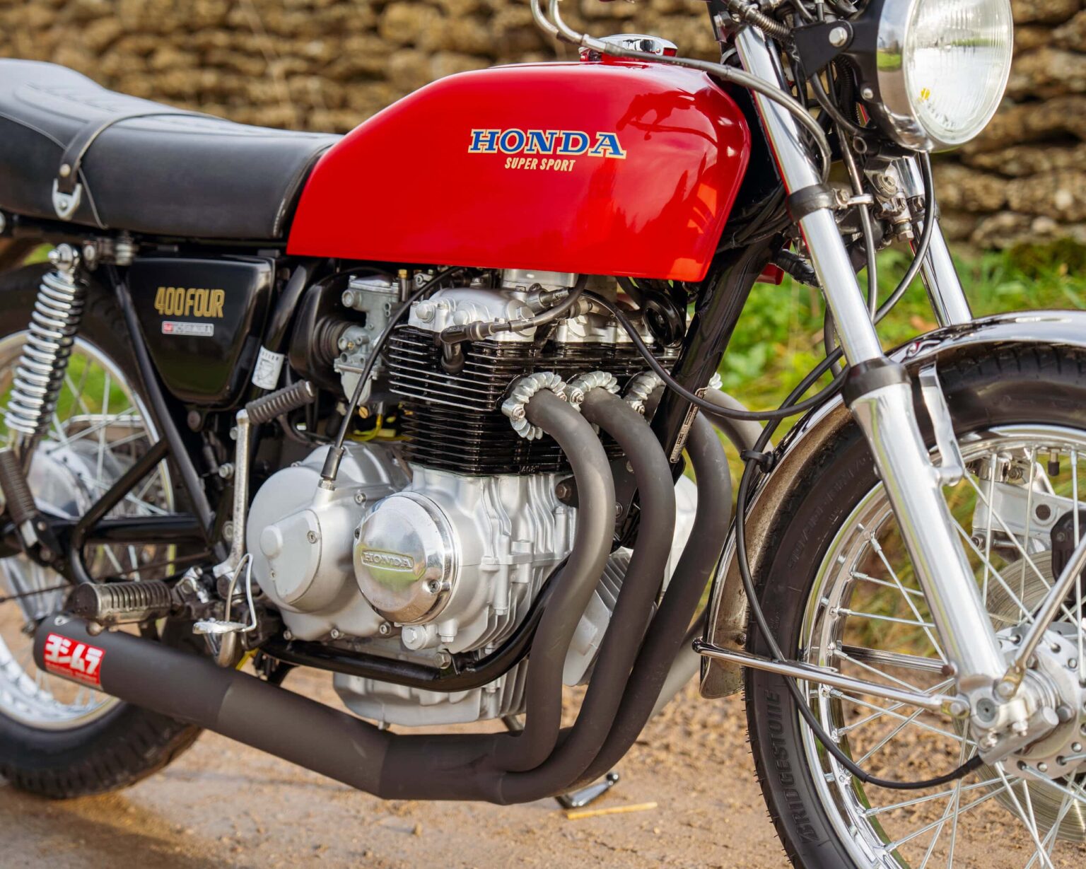 Vintage Honda CB400F motorcycle with red fuel tank and black exhaust pipes.
