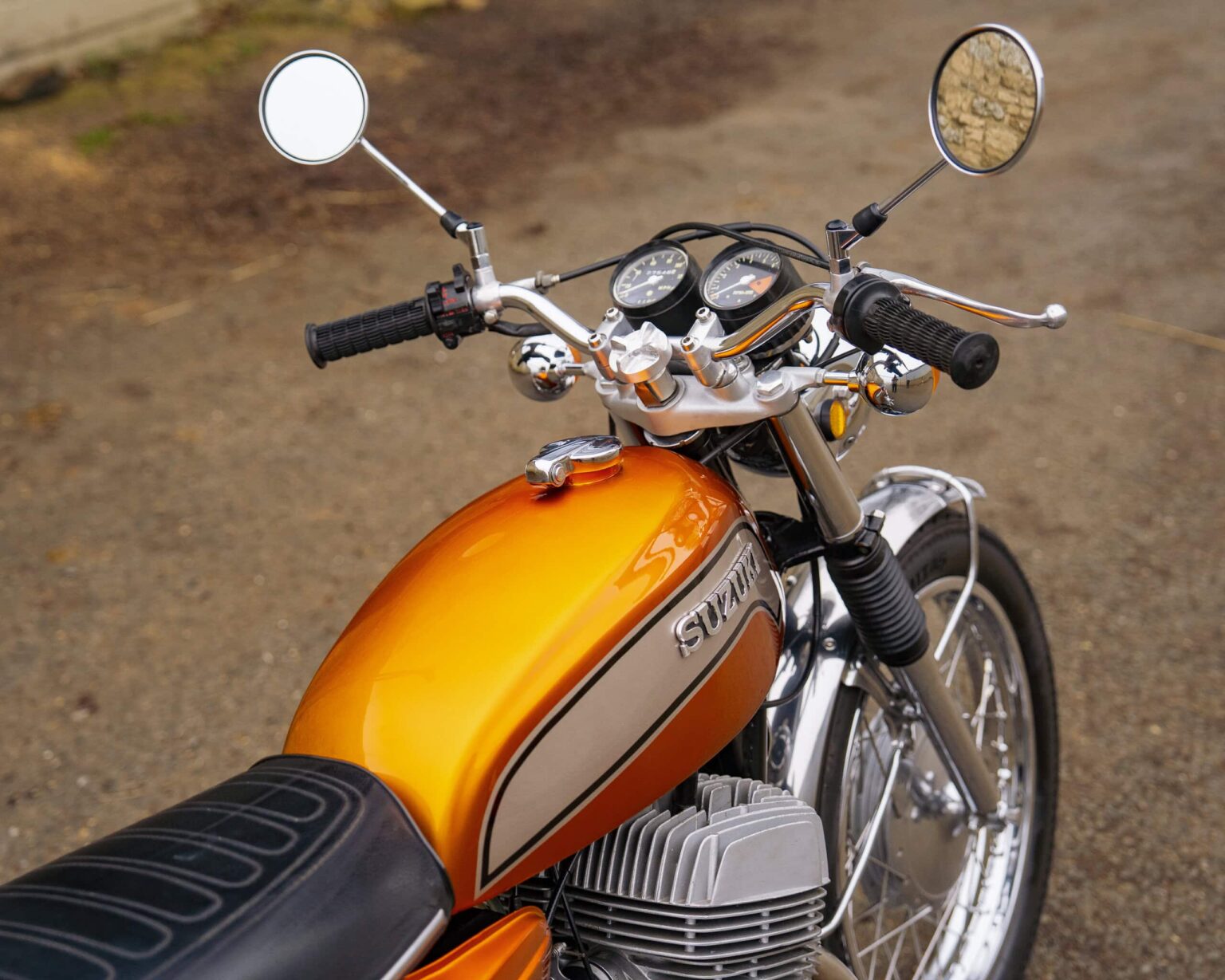 Motorcycle with orange fuel tank, chrome accents, and dual rearview mirrors.