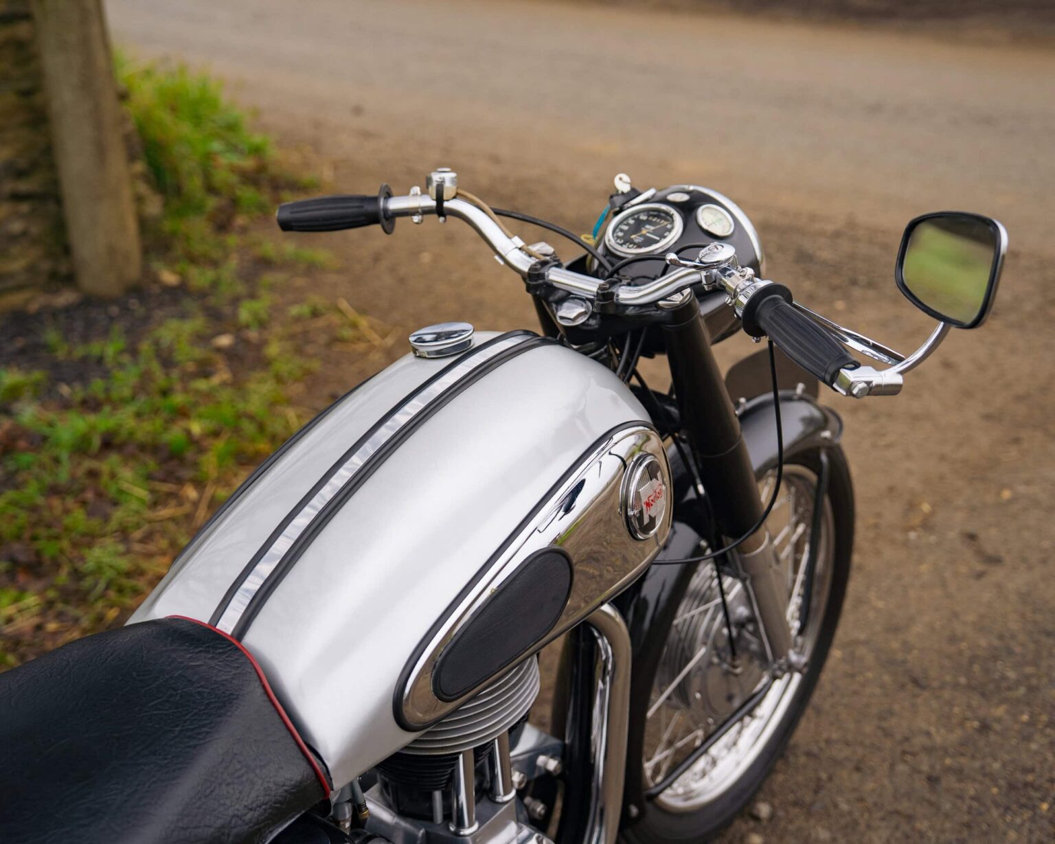 Motorcycle parked on a rural road with greenery in the background.