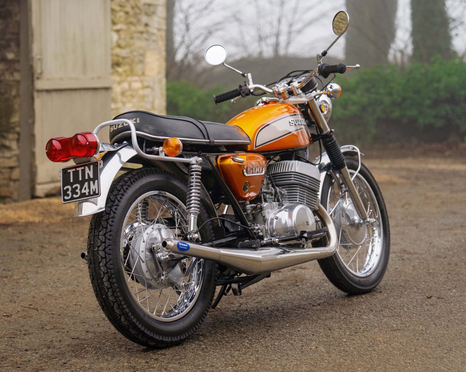 Vintage orange Suzuki motorcycle with chrome details and black seat.