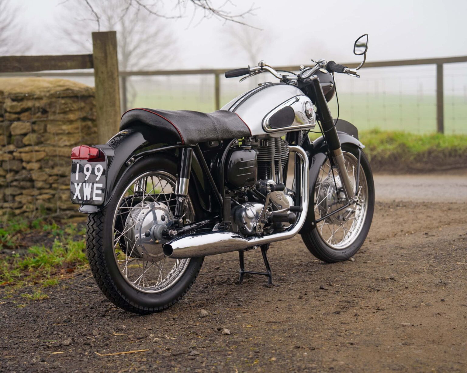 Vintage motorcycle with black and chrome finish, parked outdoors on a foggy day.