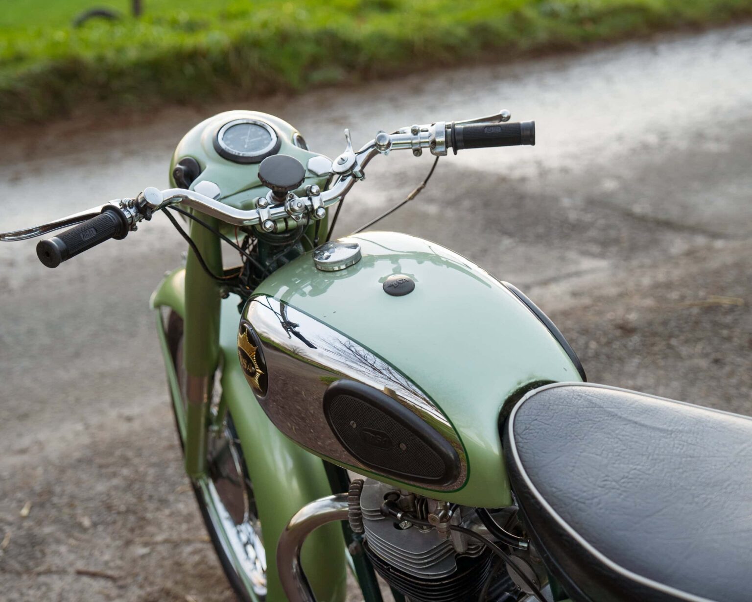 Vintage green motorcycle with black seat and chrome details.