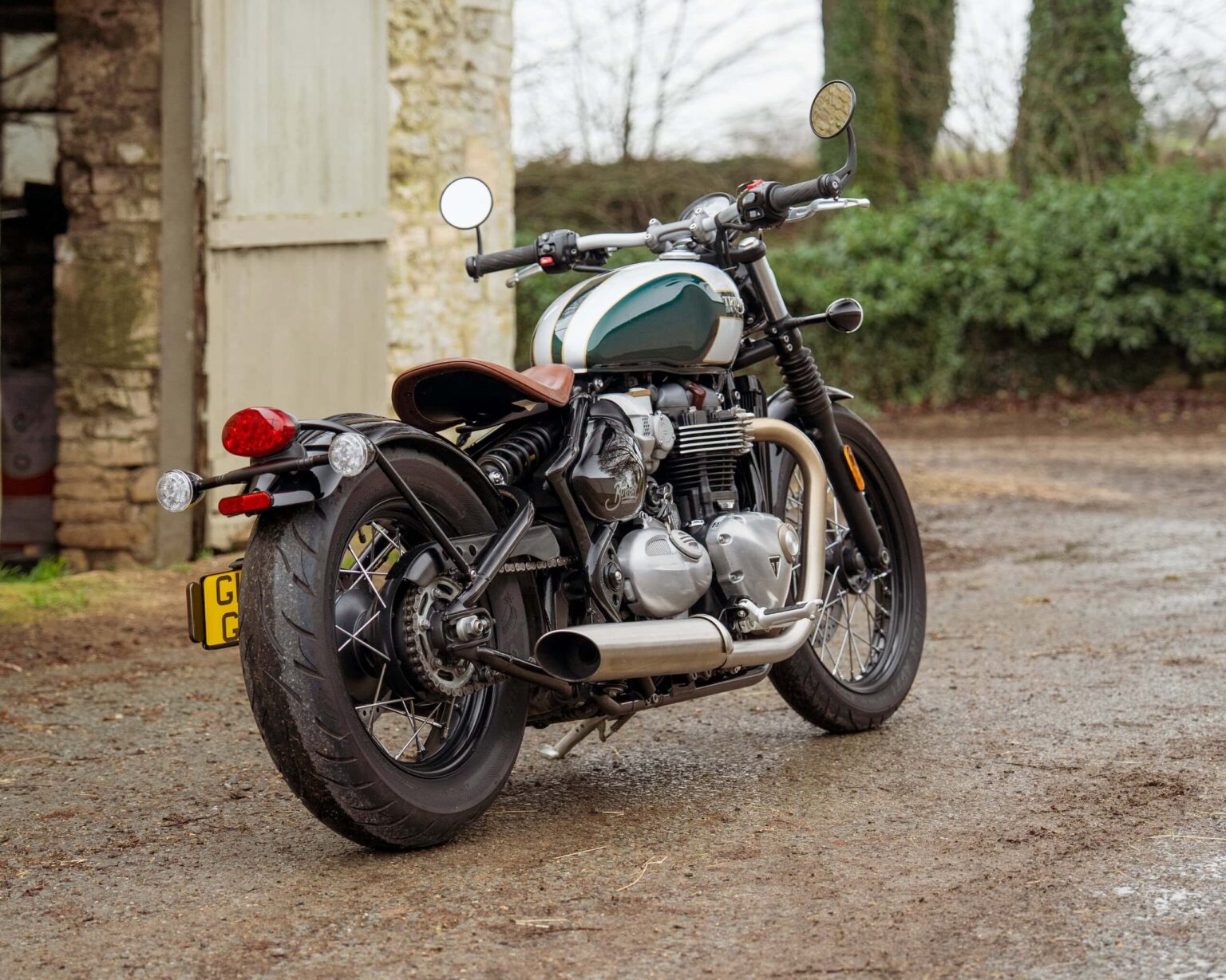 Motorcycle with vintage design parked outdoors near an old stone building.