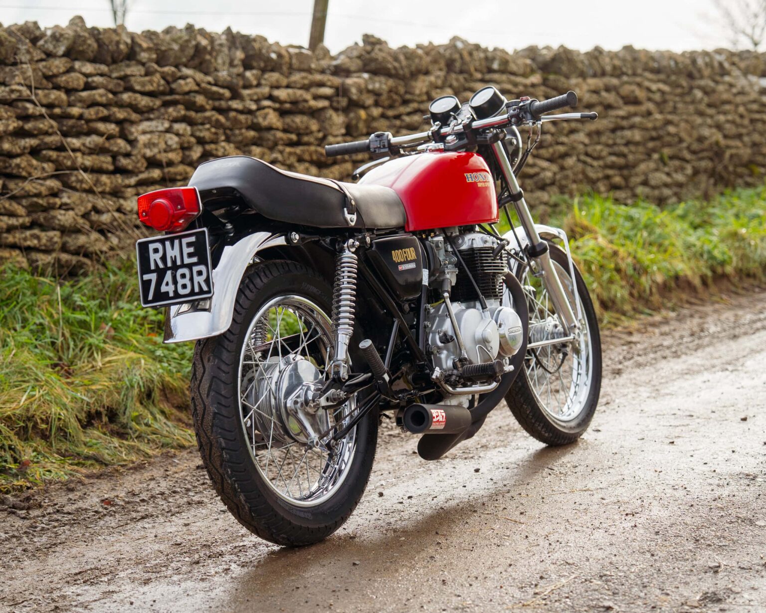 Vintage red and black motorcycle parked on a rural country road.