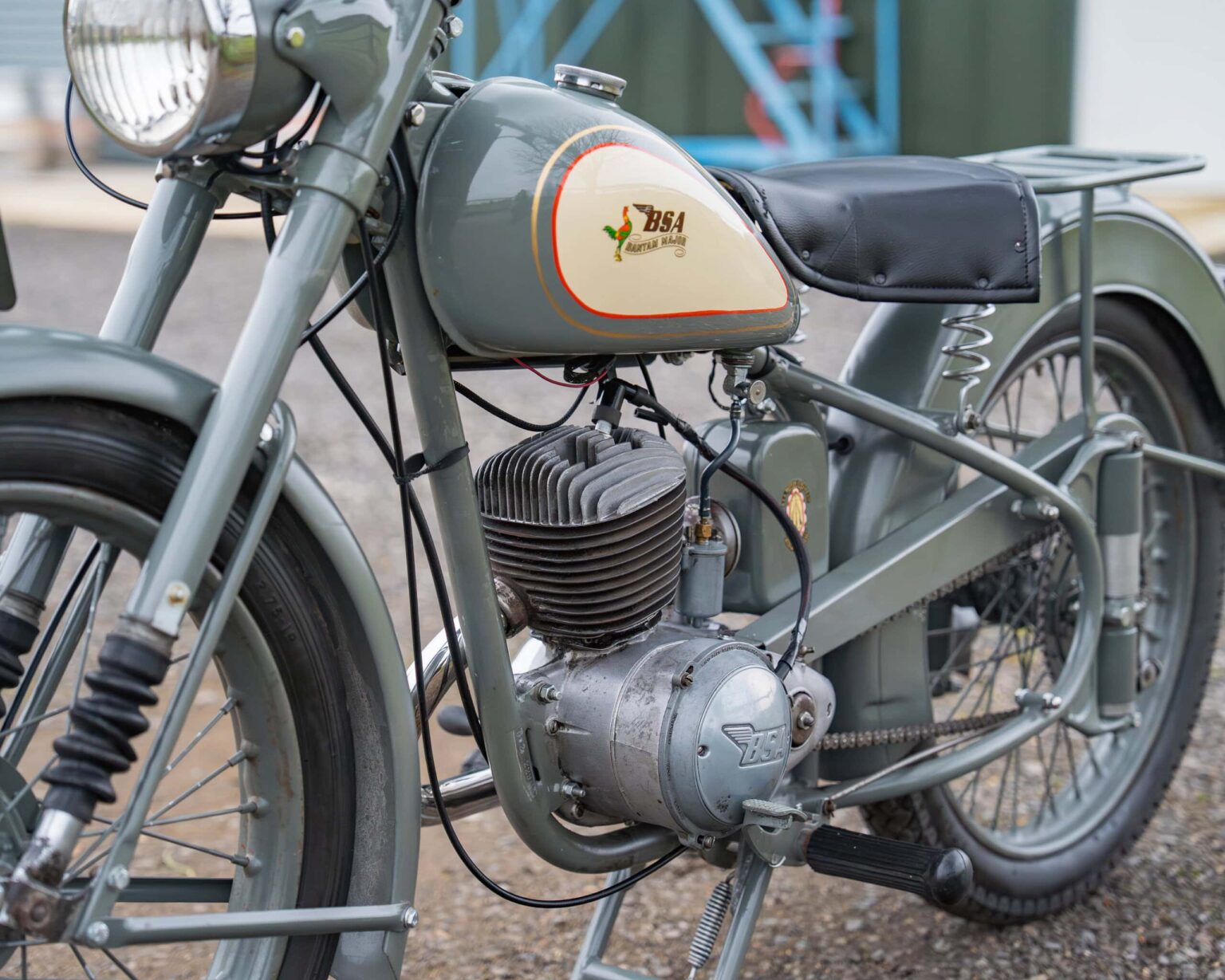 Vintage motorcycle with grey body and black seat, displayed outdoors.