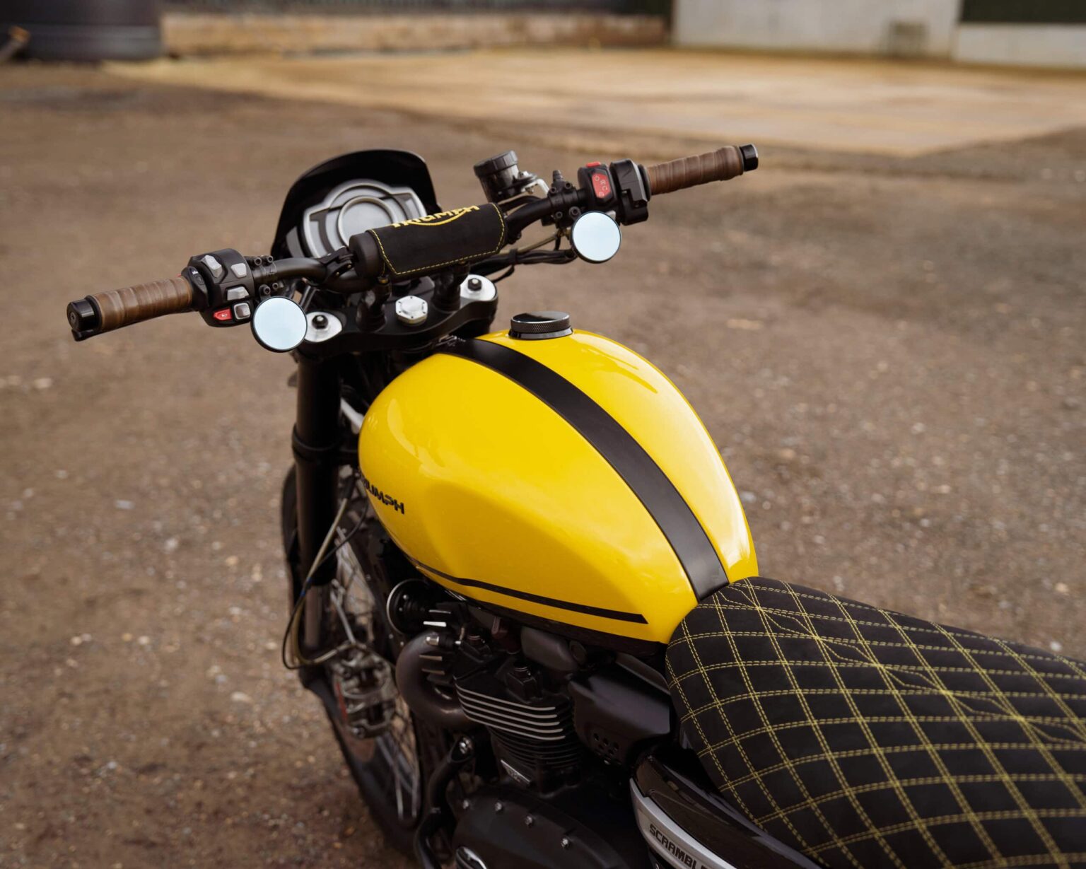 Motorcycle with yellow fuel tank, black seat, and handlebar controls.