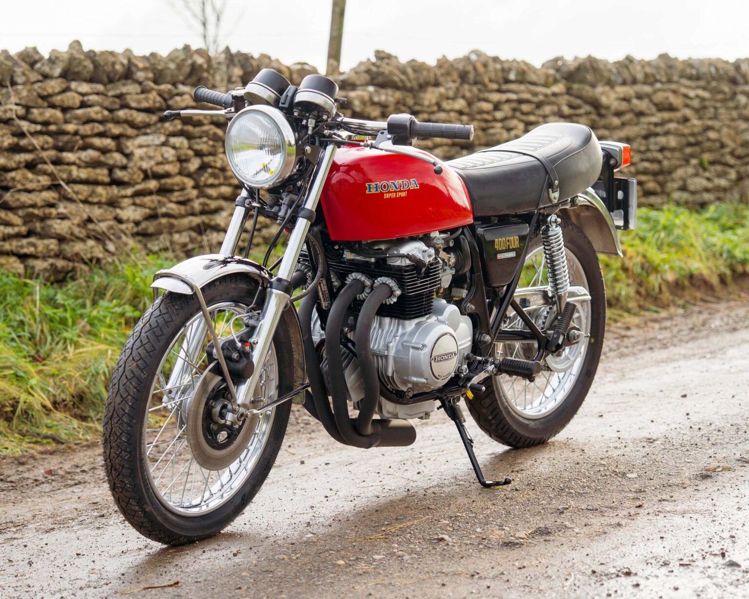 Honda CB750 vintage motorcycle on a rural road with stone wall background.