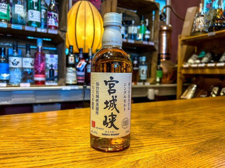 A bottle of Miyagi whisky displayed on a wooden bar counter with shelves of various spirits in the b.