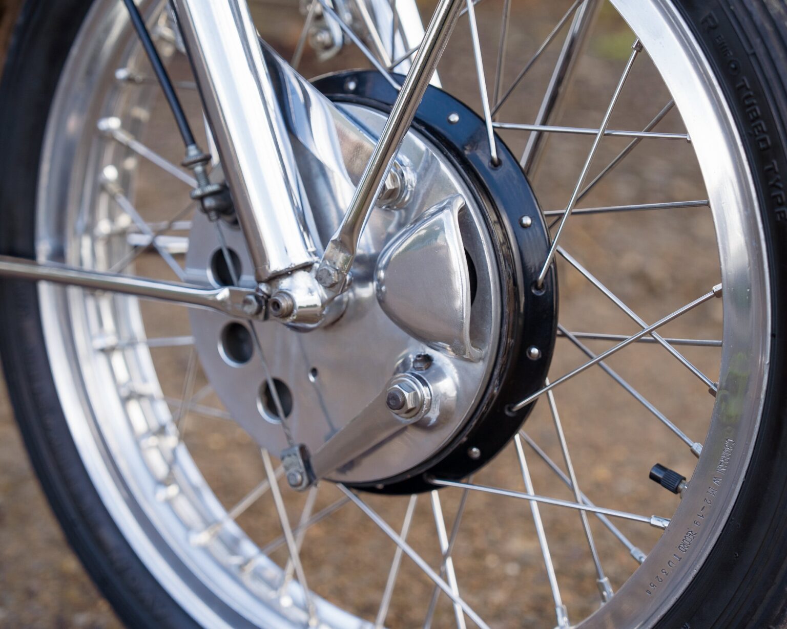 Up of a vintage motorcycle wheel and hub, showcasing detailed metalwork and spokes.