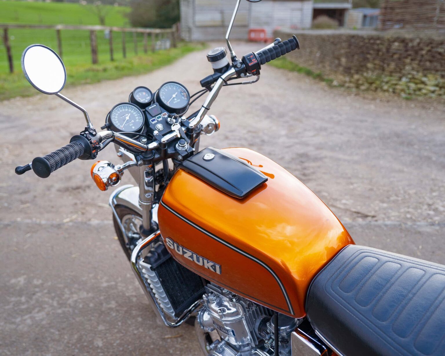 Vintage Suzuki motorcycle with orange fuel tank and black seat.