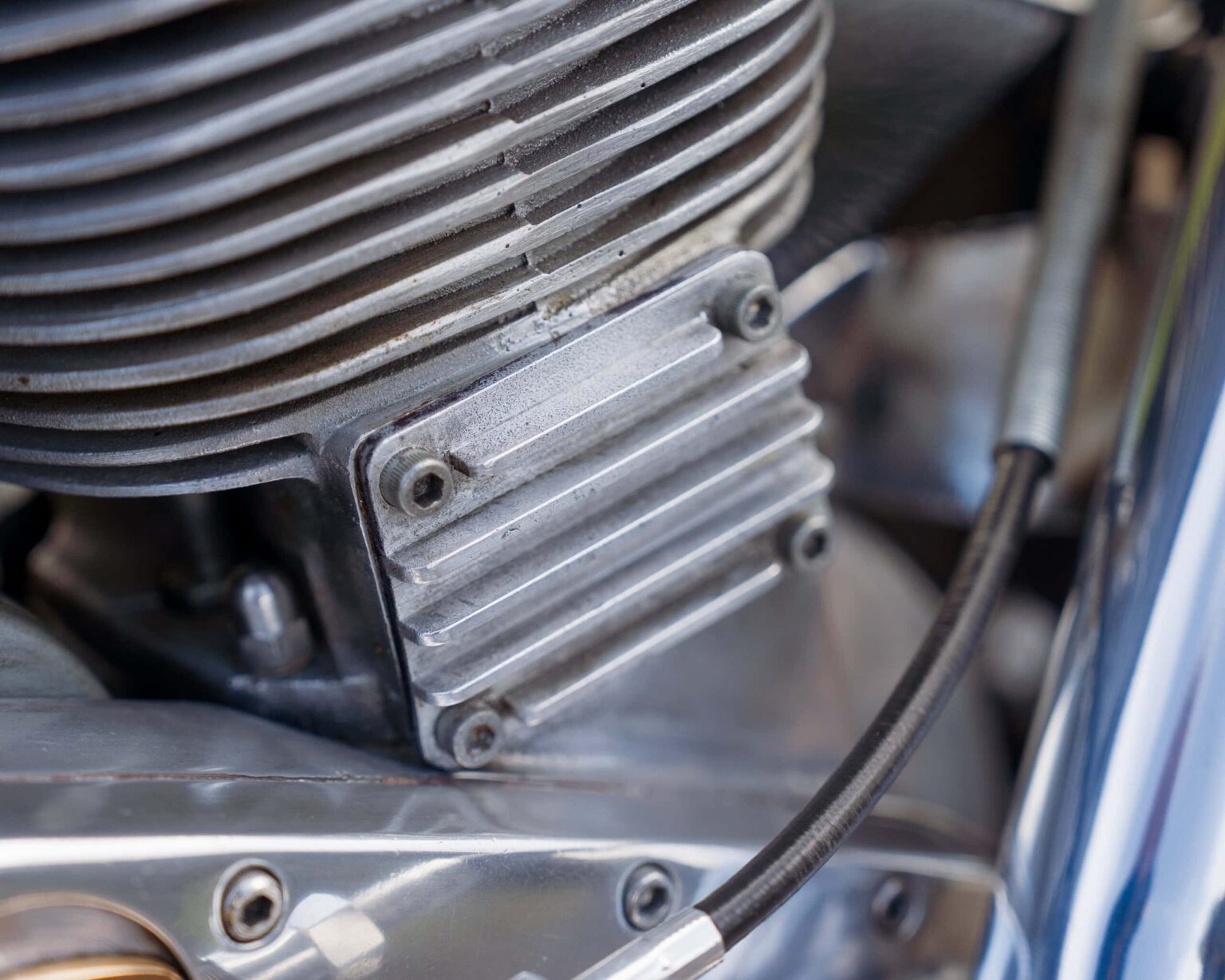 Up of a motorcycle engine cylinder head with cooling fins and bolts.