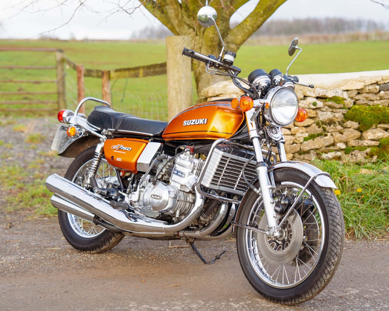 Vintage Suzuki motorcycle parked outdoors in a rural setting.