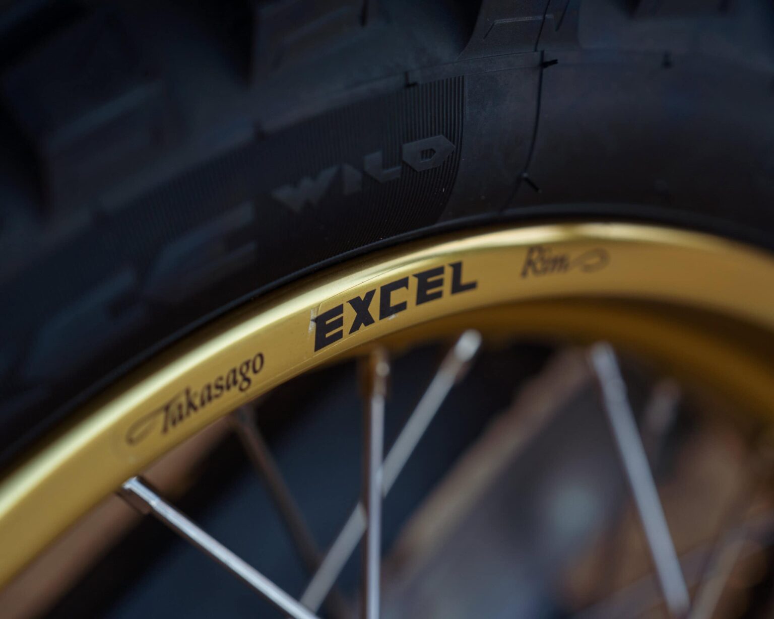 Close-up of a bicycle wheel with gold rim and branded spokes.