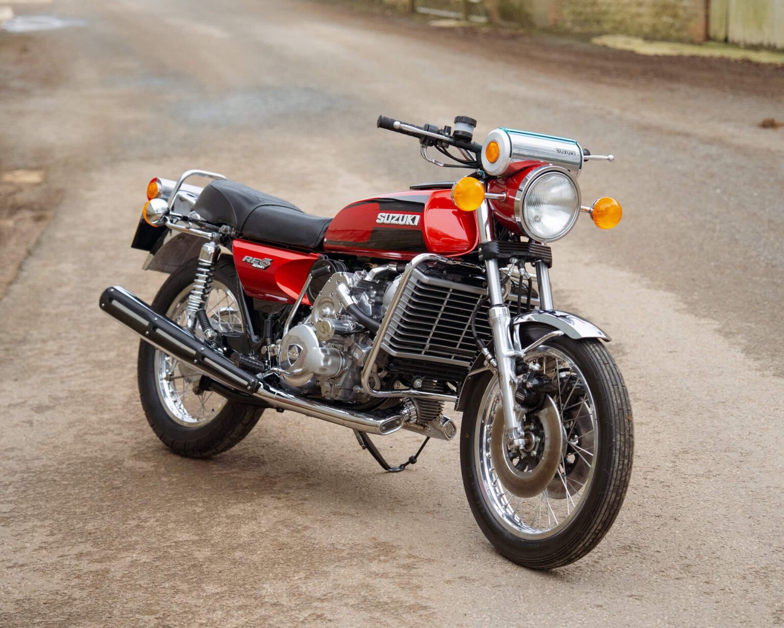 Vintage Suzuki motorcycle parked on a dirt road.