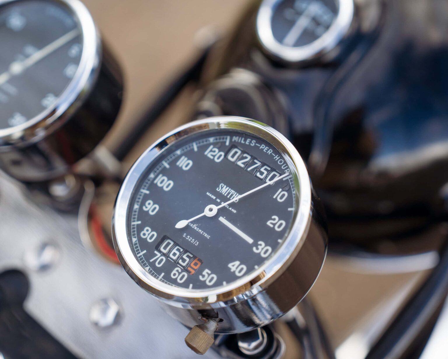 Vintage motorcycle speedometer with chrome finish and black dial.