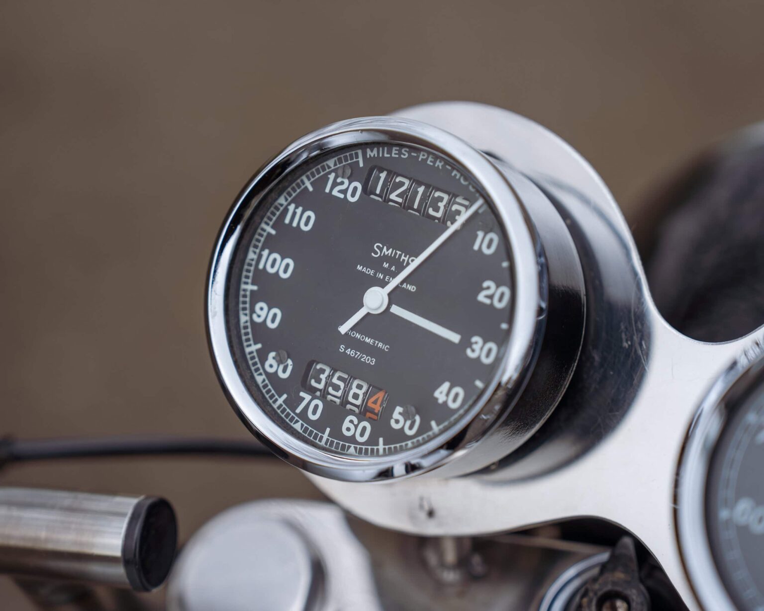 Vintage motorcycle speedometer with odometer and speed gauge.