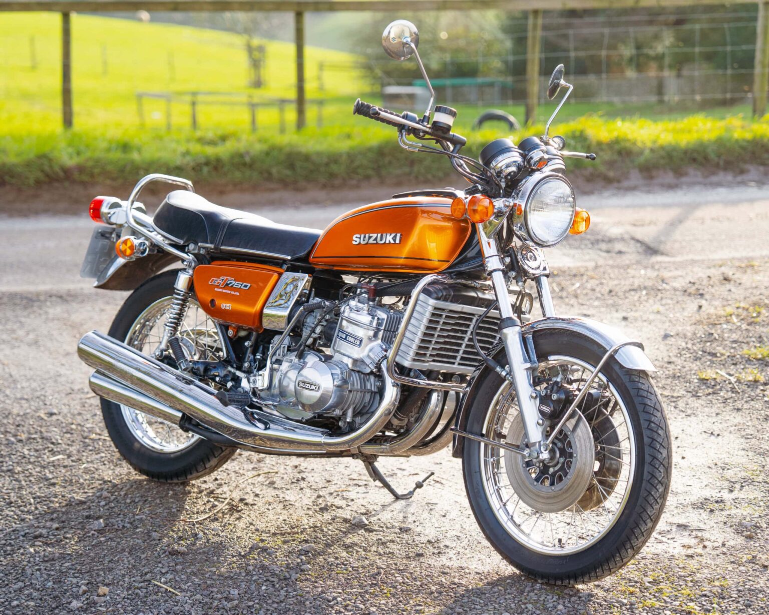 Vintage Suzuki motorcycle parked outdoors with a rural background.
