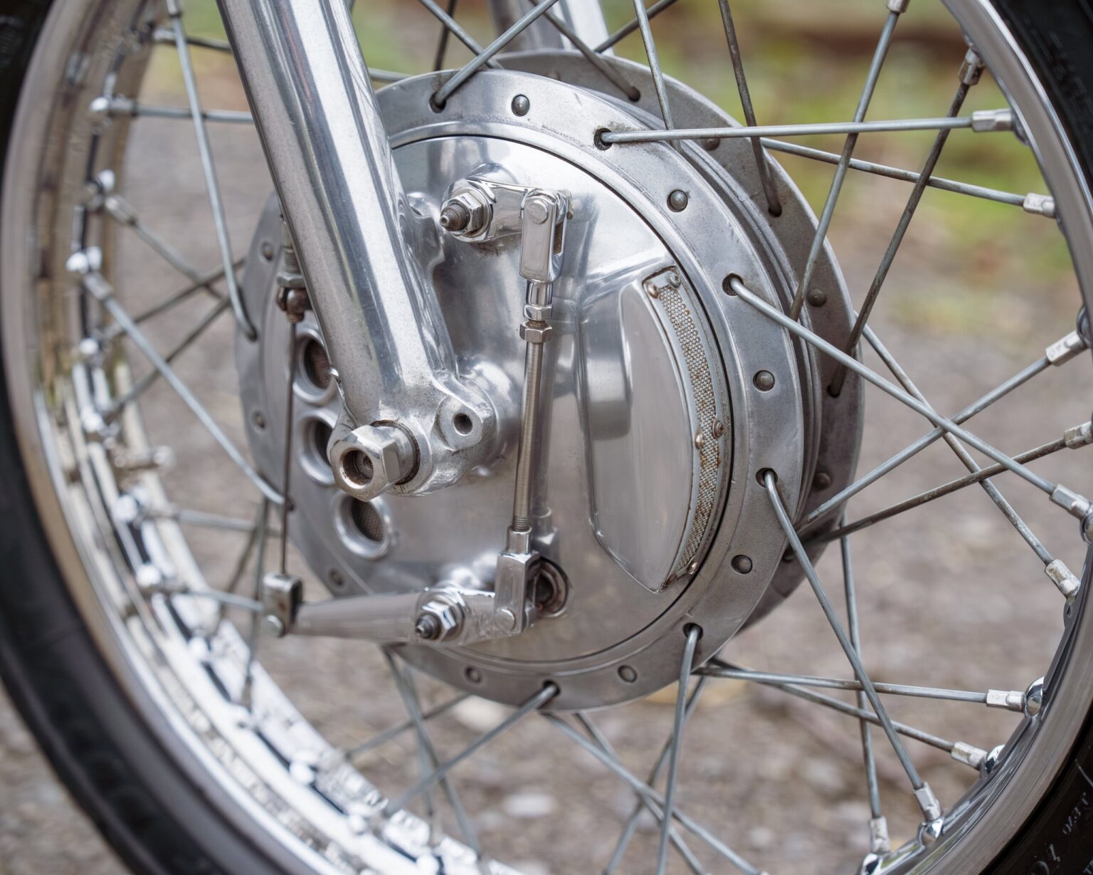 Close-up of a vintage motorcycle wheel and hub with spokes and axle.