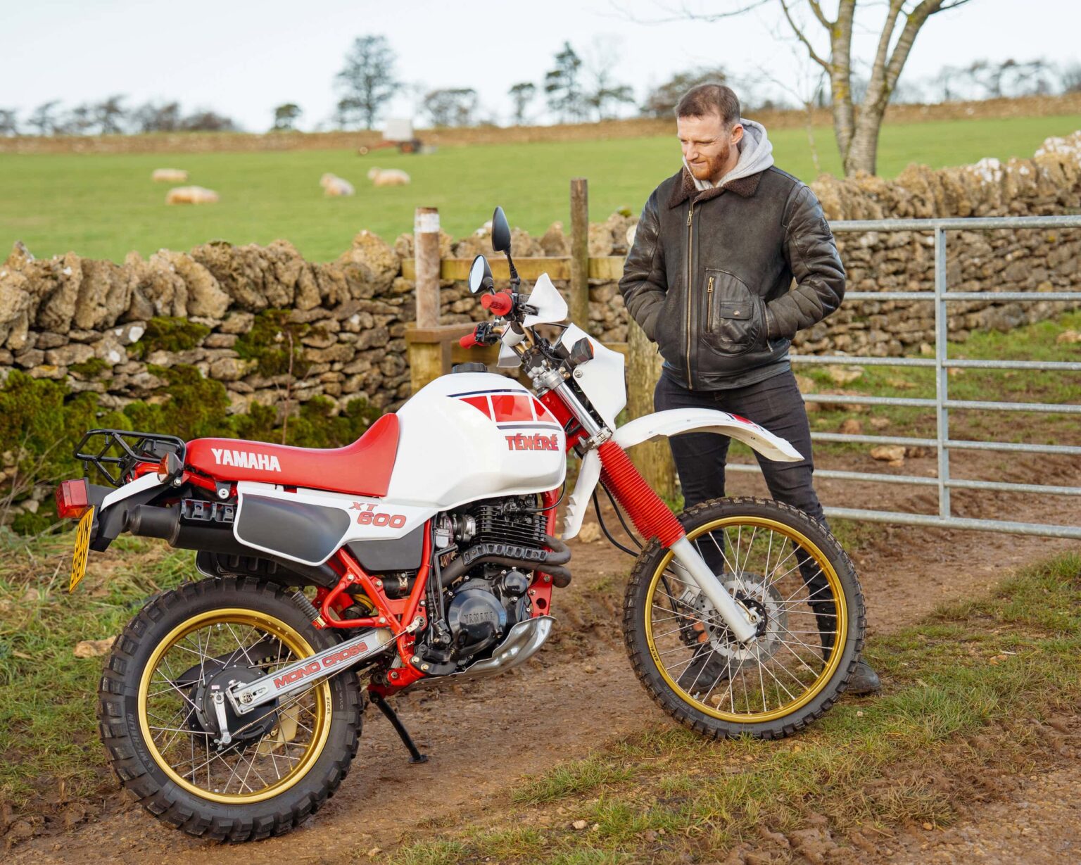 Yamaha XT600 motorcycle parked outdoors in a rural landscape with a man checking it.