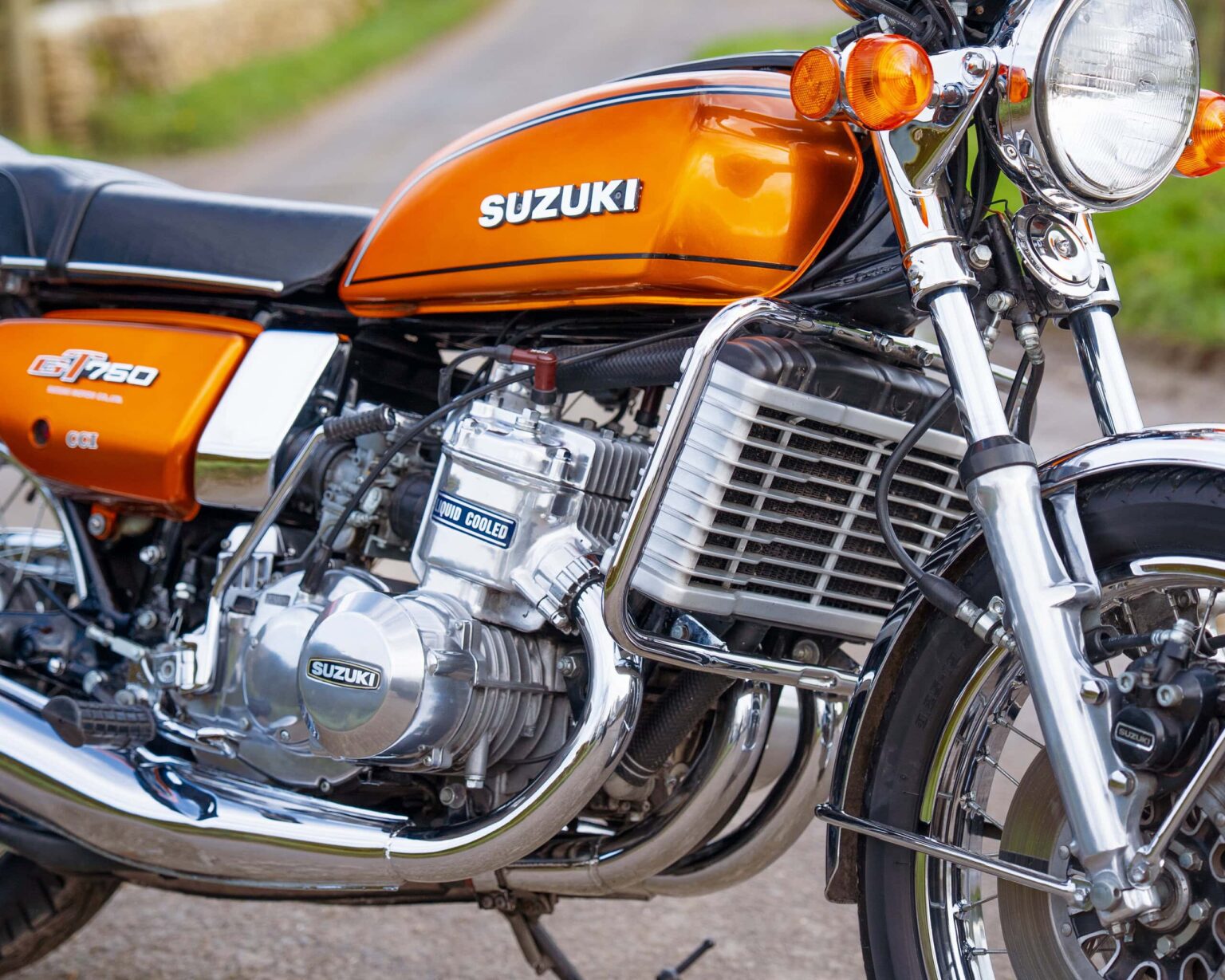 Vintage Suzuki GT750 motorcycle with orange tank and chrome engine.