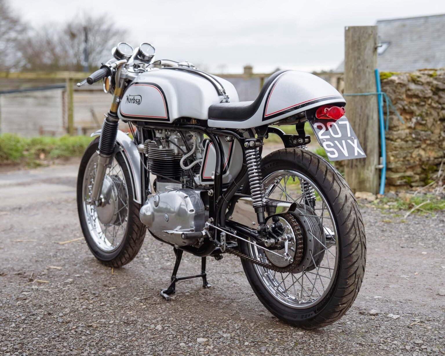 Vintage motorcycle with white and black paint, classic design, and racing number plate.